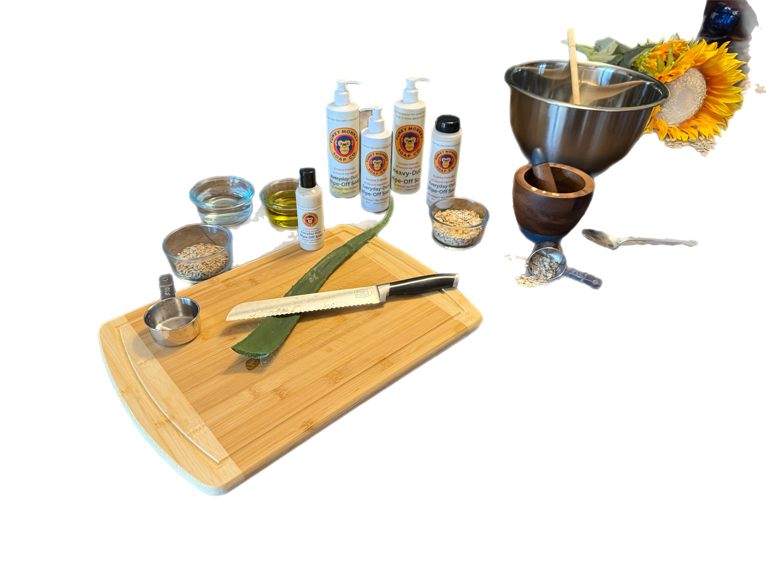 Set of kitchen utensils and ingredients on a wooden cutting board with bottles of Funky Monkey Soap in the background.