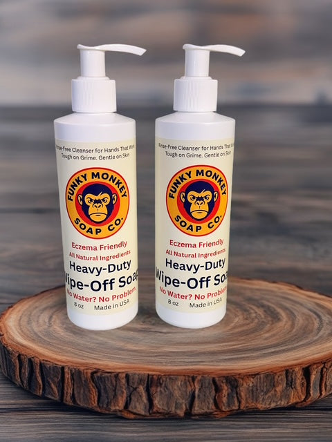 Two bottles of Funky Monkey Soap Co. Heavy-Duty Wipe-Off Soap on a wooden surface with a blurred background.