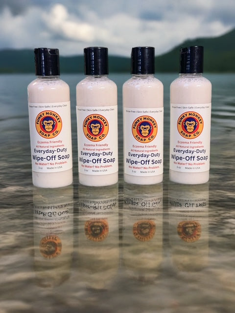 Four bottles of Everyday-Duty Wipe-Off Soap from Funky Monkey Soap Co. on a reflective water surface with mountains in the background.
