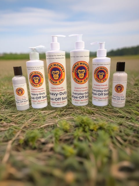 Set of Funky Monkey Soap Co. bottles on a grassy field with a blue sky.