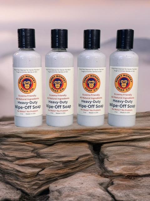 Four bottles of Heavy-Duty Wipe-Off Soap from Funky Monkey Soap Co. on a stone surface.
